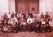 Jindřich Noháček (jako ředitel) s dětmi z 1. třídy obecné školy chlapecké na dvoře školy na Slovanském náměstí 2 (školní rok 1915/1916). Spolu s ním je na snímku i paní učitelka Heřma Jelínková. Fotografii z brožury Královo Pole...